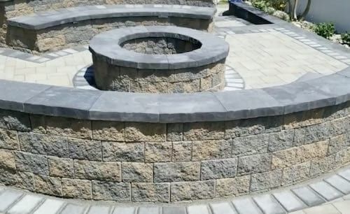 Stone fire pit with curved seating and surrounding patio.