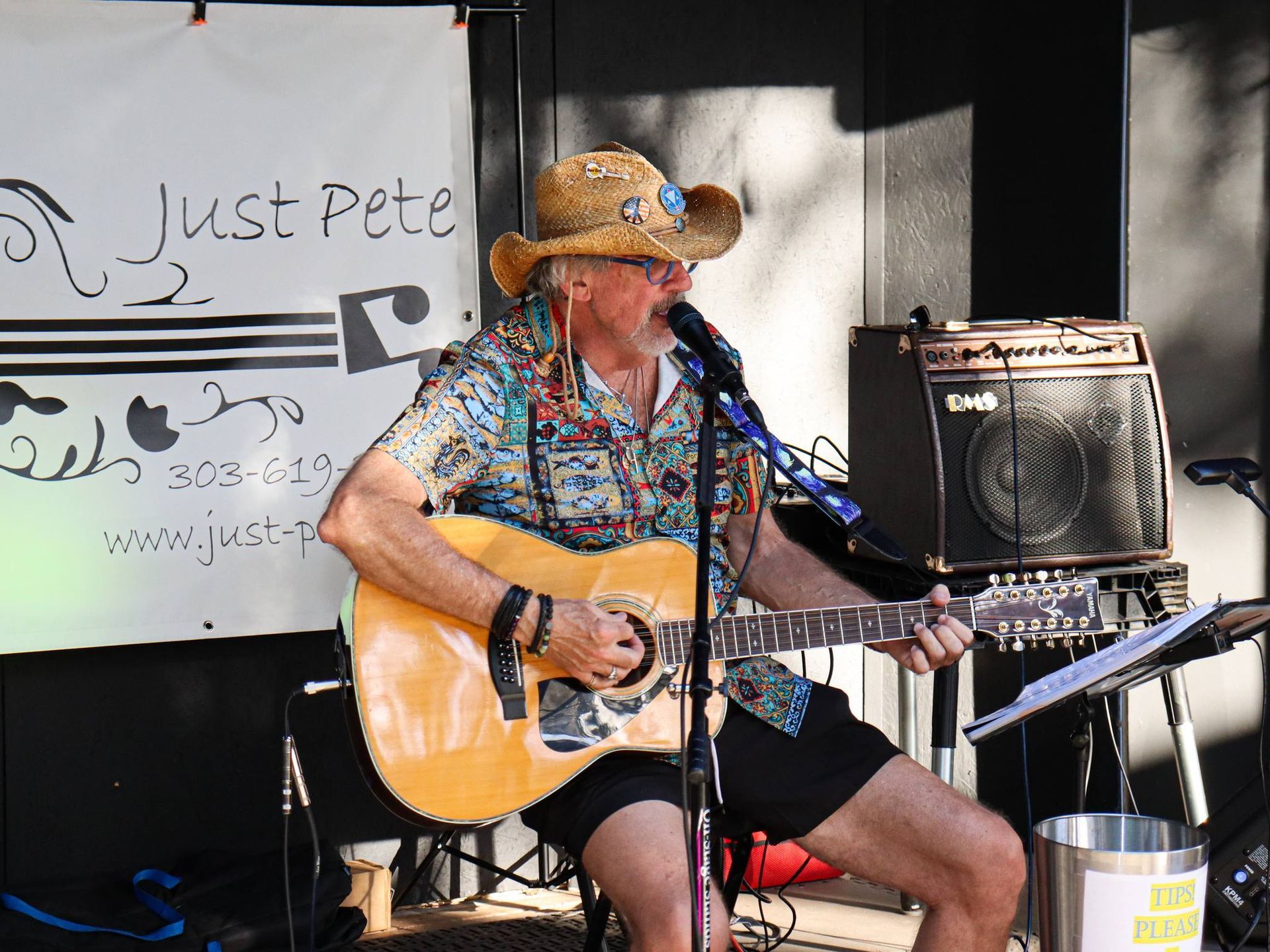 Pete Moran in a cowboy hat is playing a guitar and singing into a microphone.