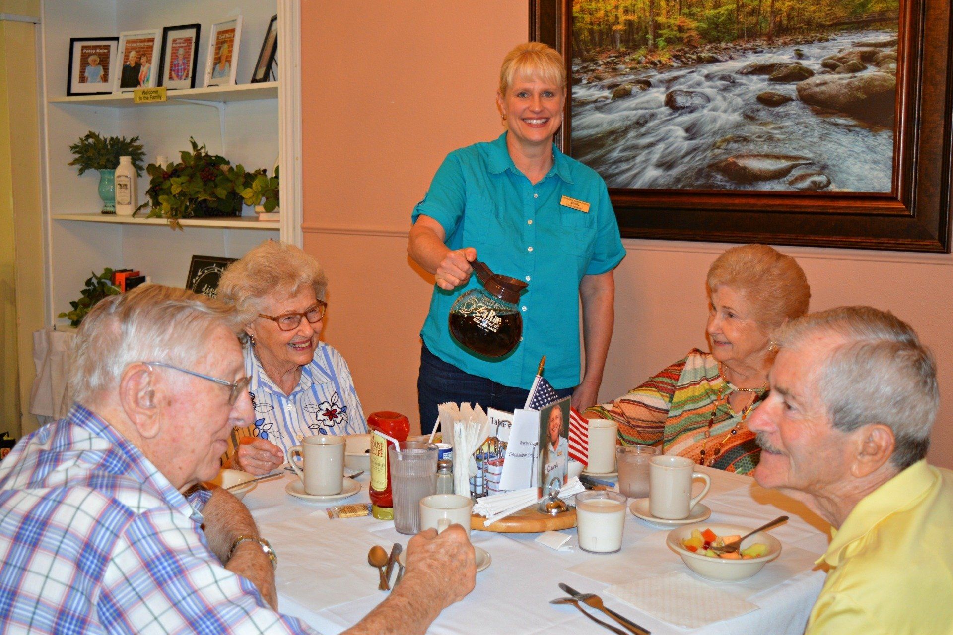 Woman serving coffee to group of seniors at a dining table.