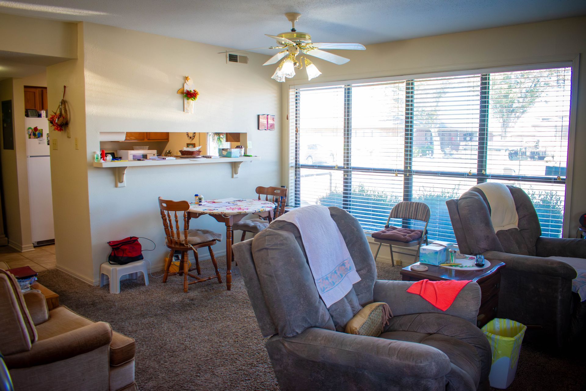 Living room with brown carpet, two recliners, table, and large window.