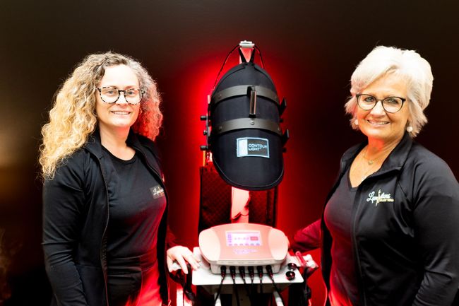 Two women are standing next to each other in front of a machine.