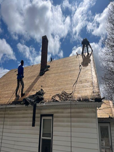 Woman in straw hat smiles, holding wine glass near a lake.