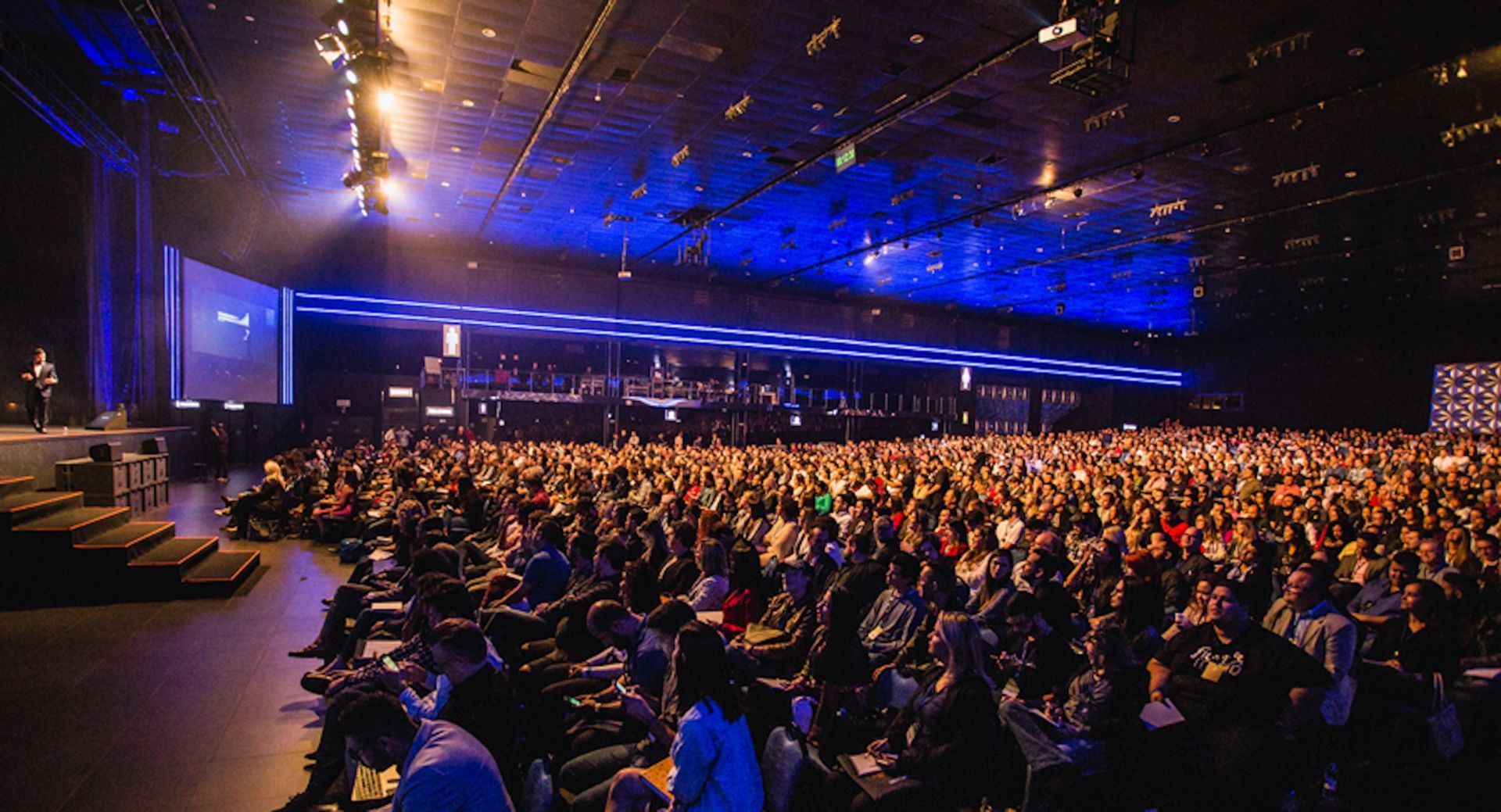 Conference hall full of attendees with speaker on stage