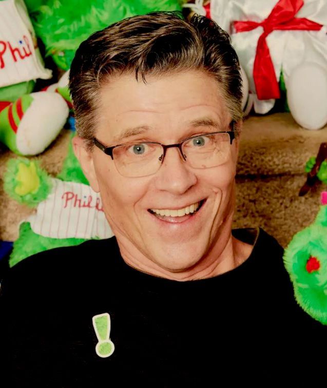 Smiling man with glasses in front of festive holiday plush decorations