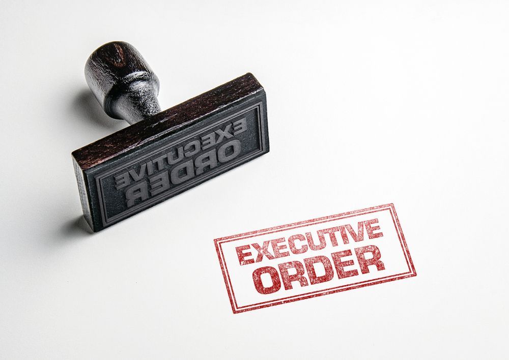A stamp labeled “EXECUTIVE ORDER” beside a black rubber stamp on a white background