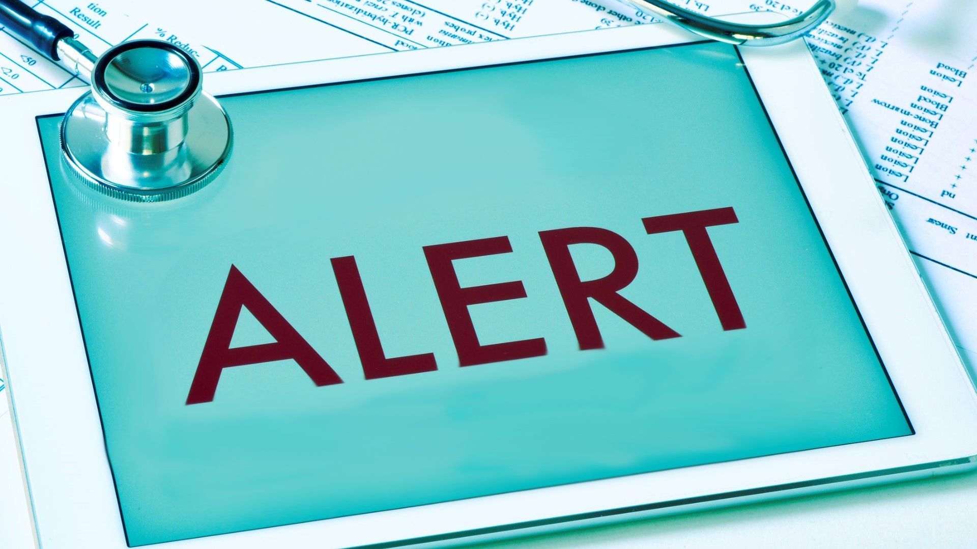 Alert text on white tablet next to stethoscope