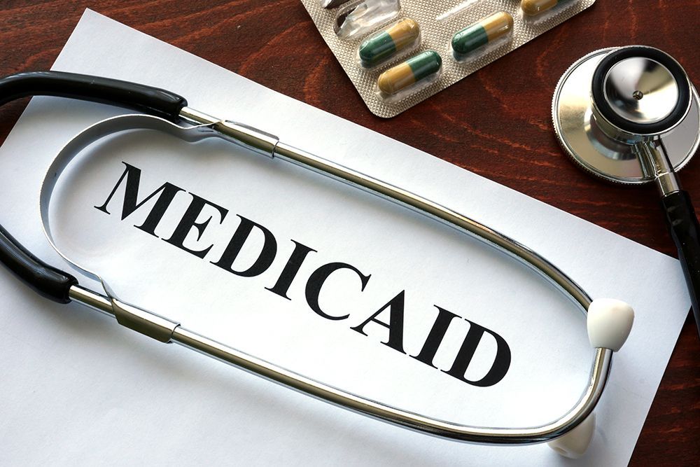 Medicaid text beside a stethoscope and pills on a desk
