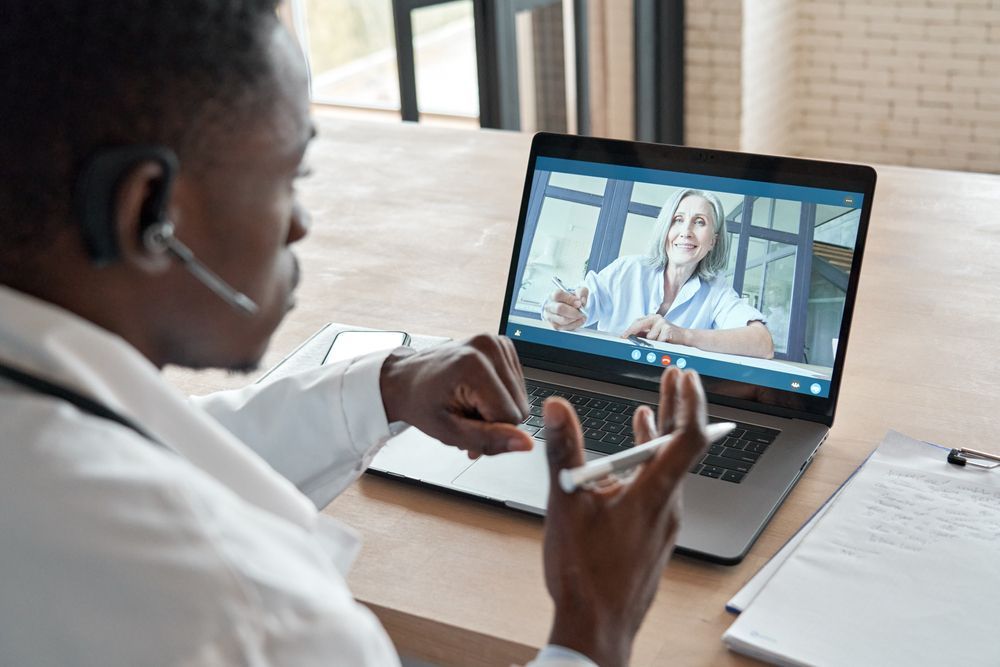 Black doctor talking to patient via webcast
