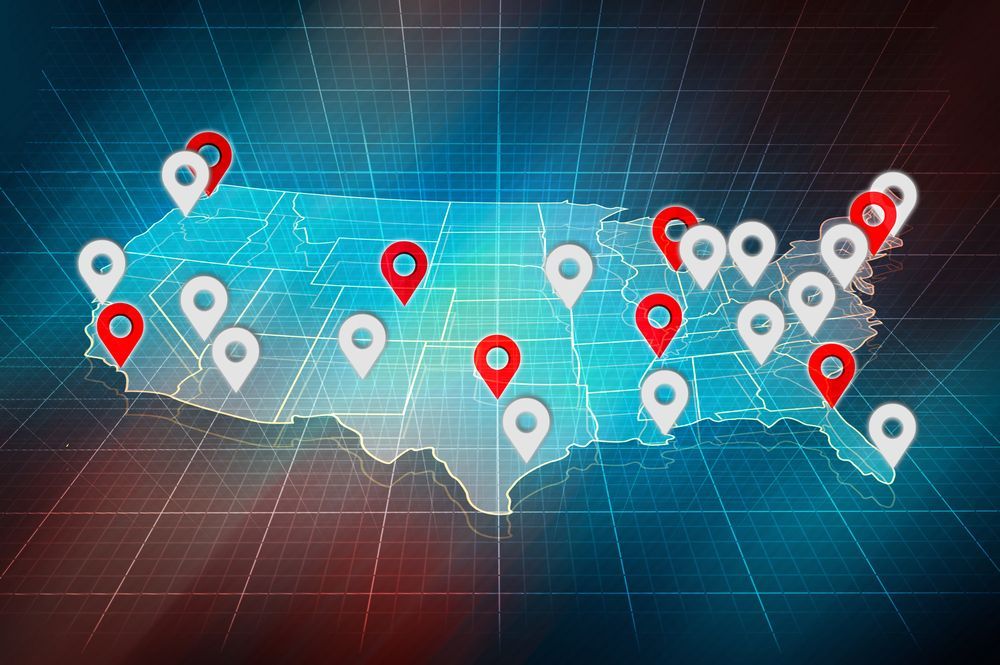A stylized map of the United States with a digital grid, featuring white and red location pins scattered across the map.