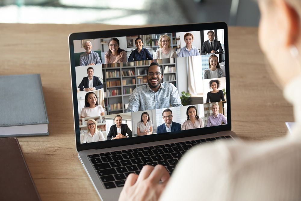 Video conference grid on a laptop with several participants in a home office setting