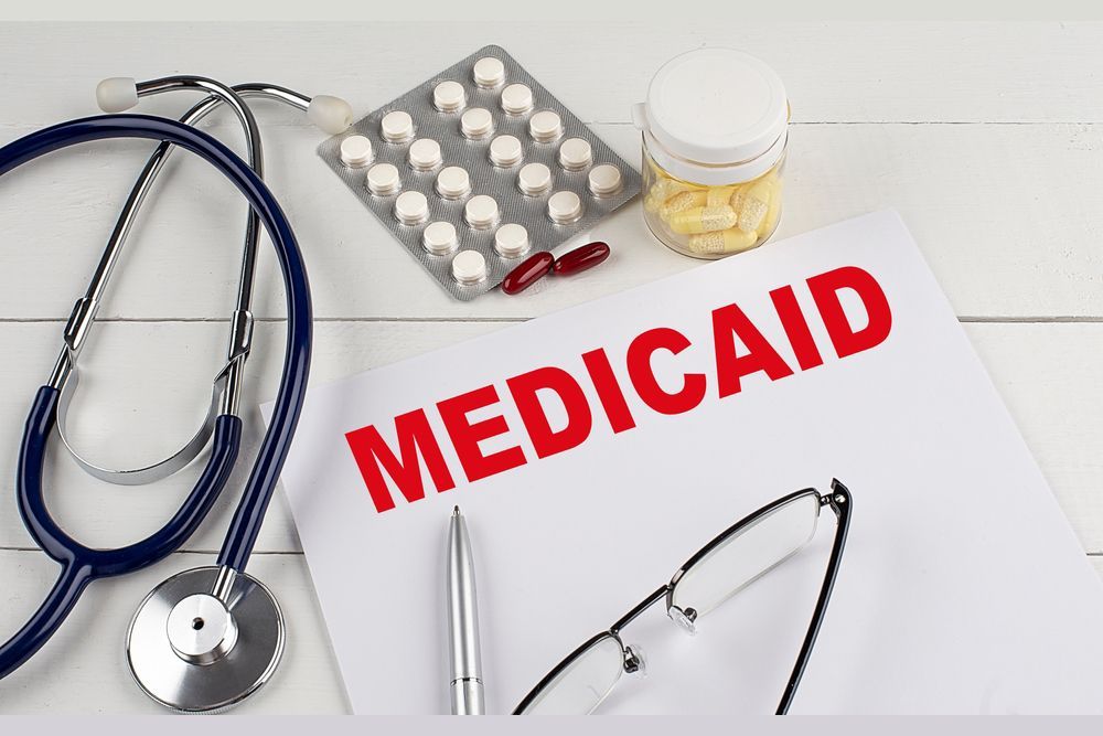 Medical supplies around a form labeled “MEDICAID,” including stethoscope, pills, and glasses