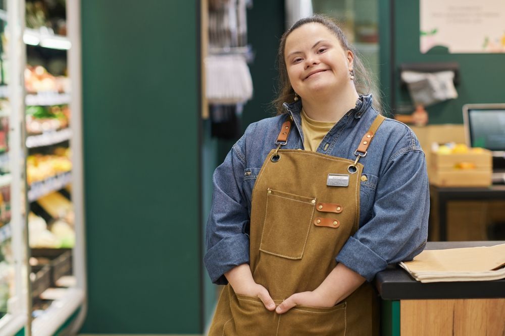 Woman with IDD working behind a counter and smiling