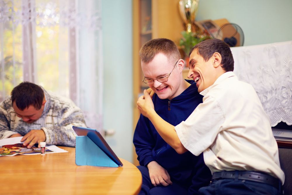 Two men with intellectual disabilities working happily on a tablet.