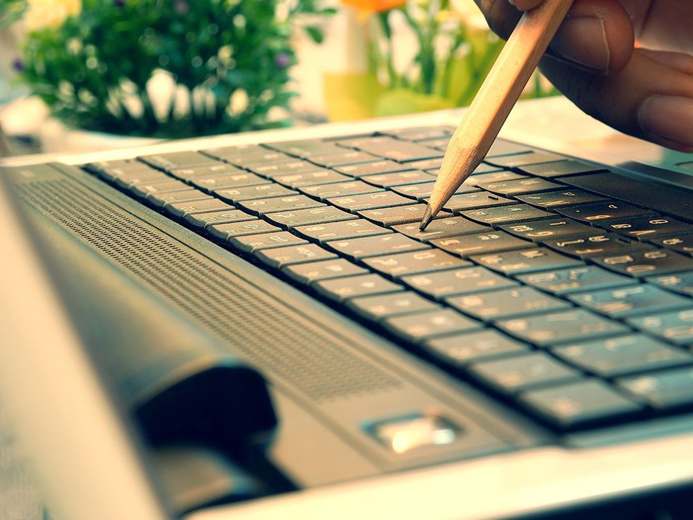 Person using pencil to tap a key on a keyboard