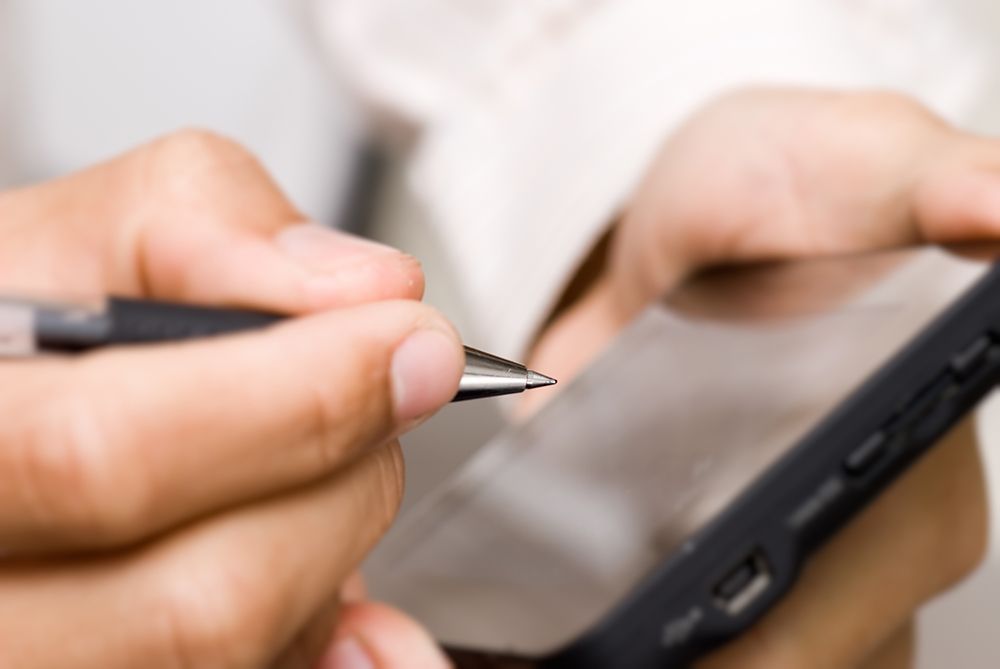 Person holding their phone and pointing at their screen with a pen