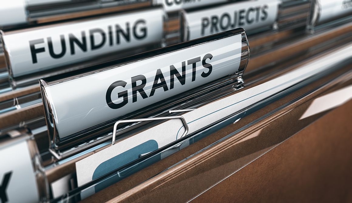File folders labeled “FUNDING,” “GRANTS,” and “PROJECTS” in a storage rack.