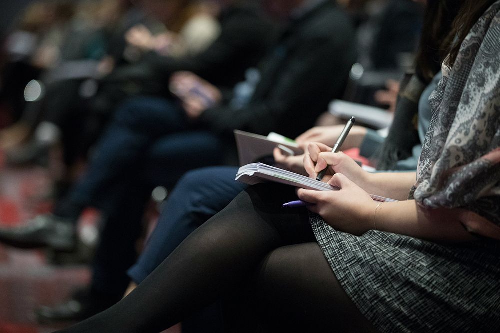 People at a conference workshop taking notes in a notepad