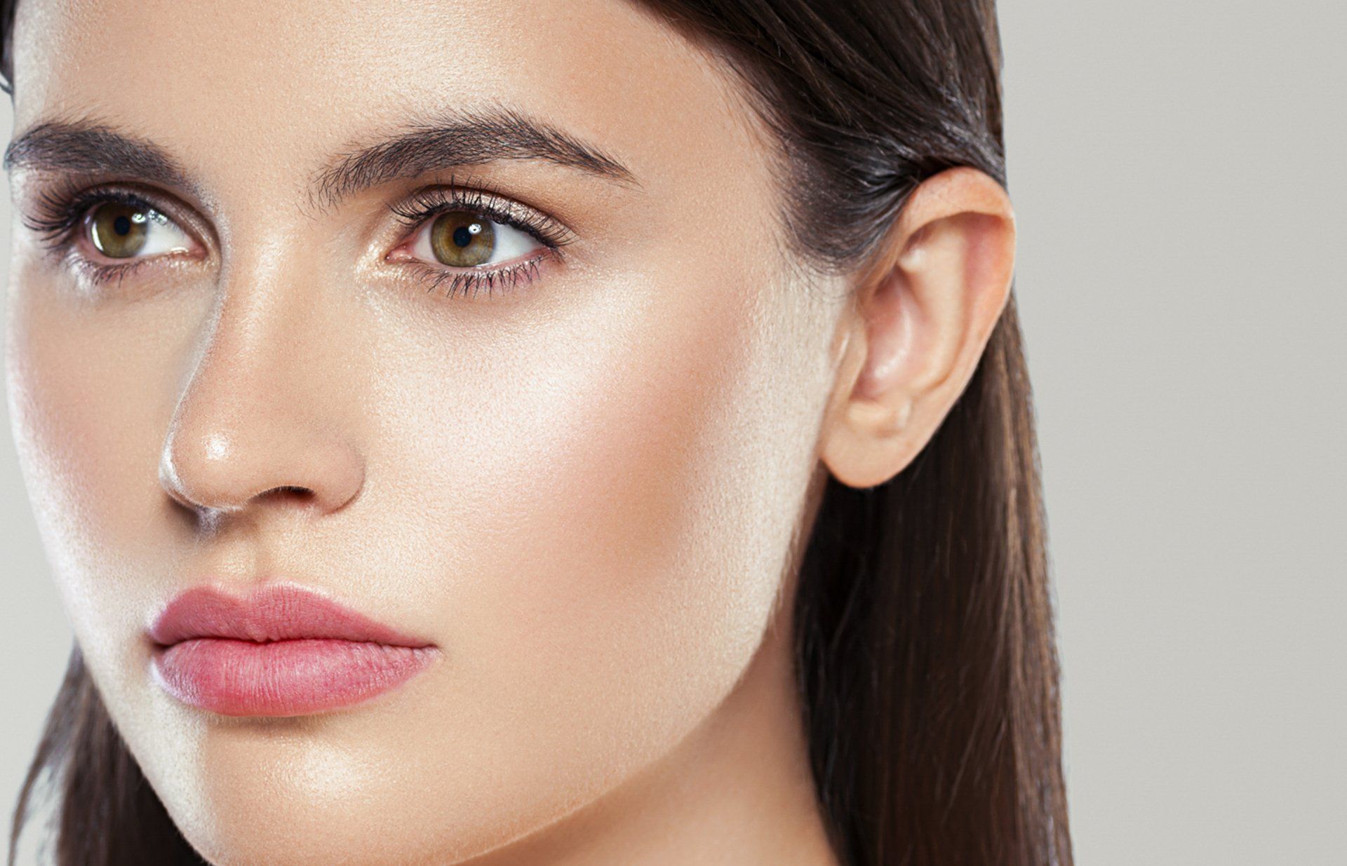 A close up of a woman 's face with a gray background.