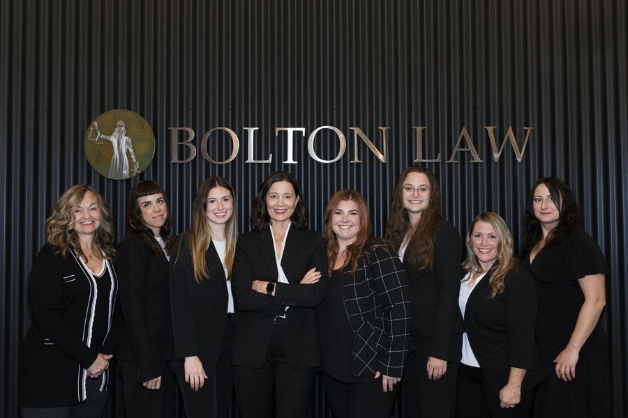 A group of women are posing for a picture in front of a bolton law sign.