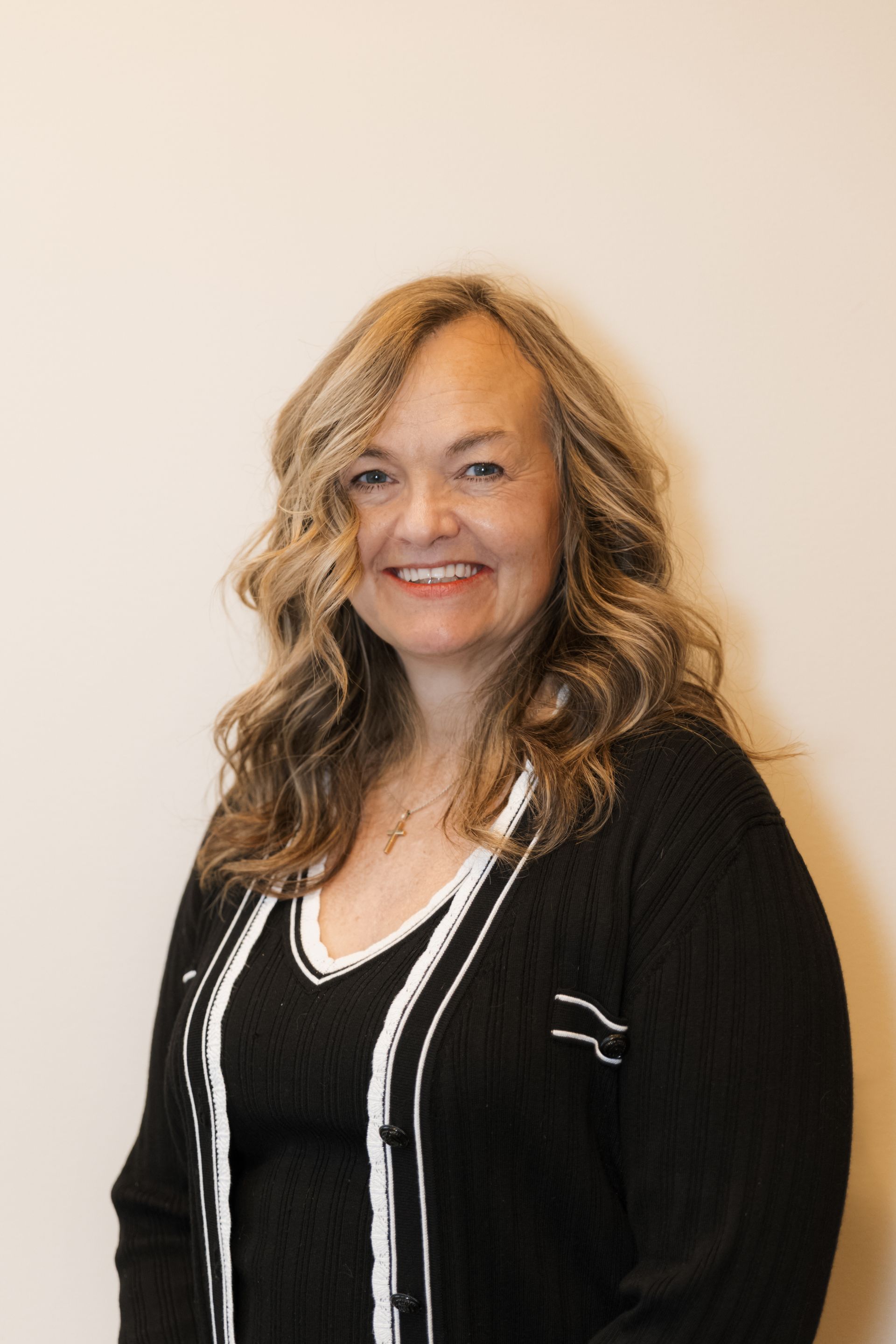 A woman in a black and white sweater is smiling for the camera.