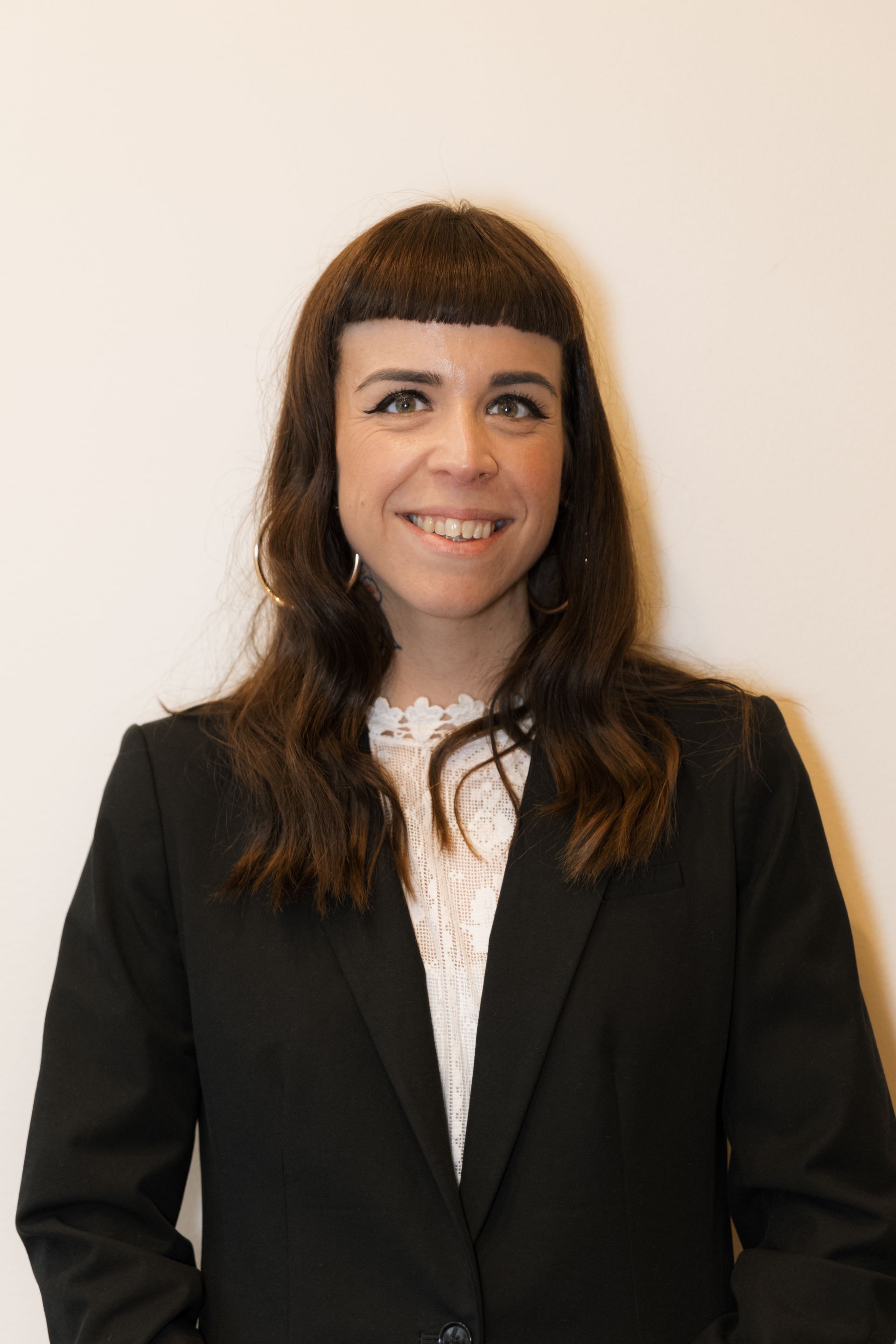 A woman in a black jacket and white shirt is smiling for the camera.