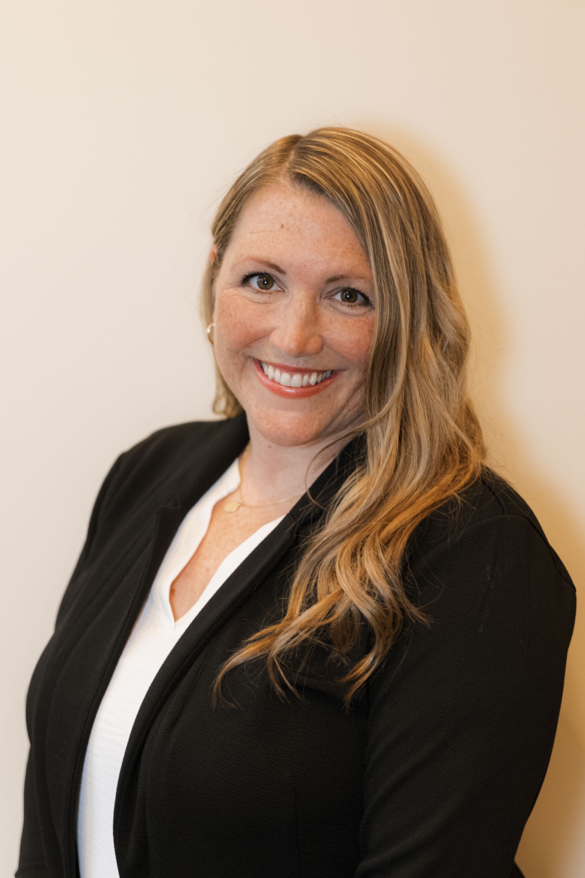 A woman in a black jacket and white shirt is smiling for the camera.