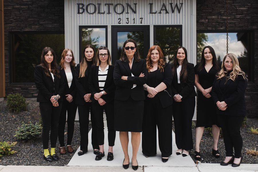 A group of women are posing for a picture in front of a bolton law sign.