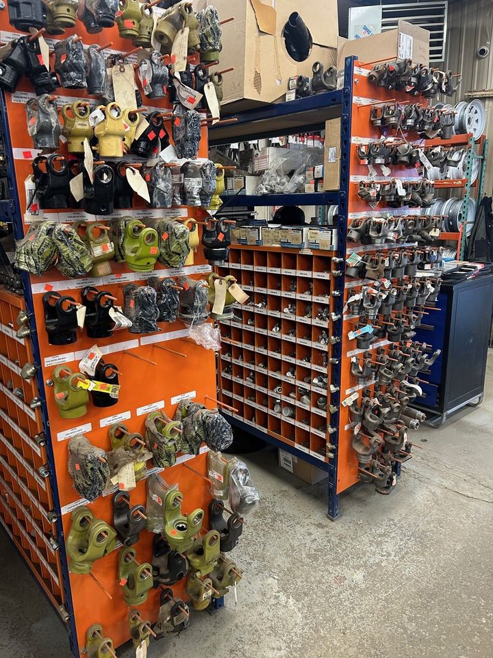 Étagères métalliques orange remplies de diverses pièces et composants industriels dans un entrepôt.