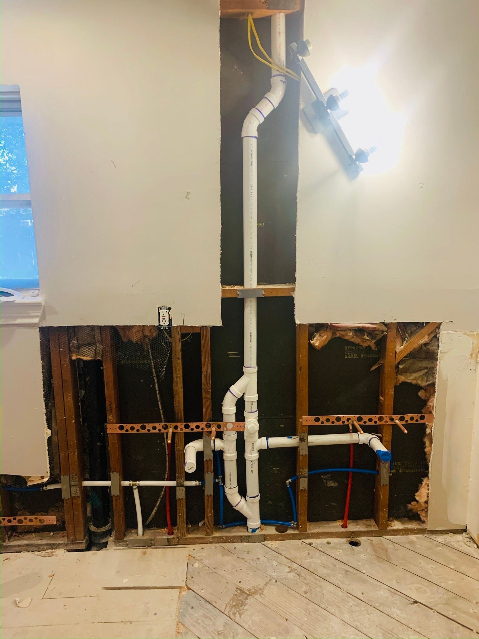 A room with a hole in the wall and pipes coming out of it.