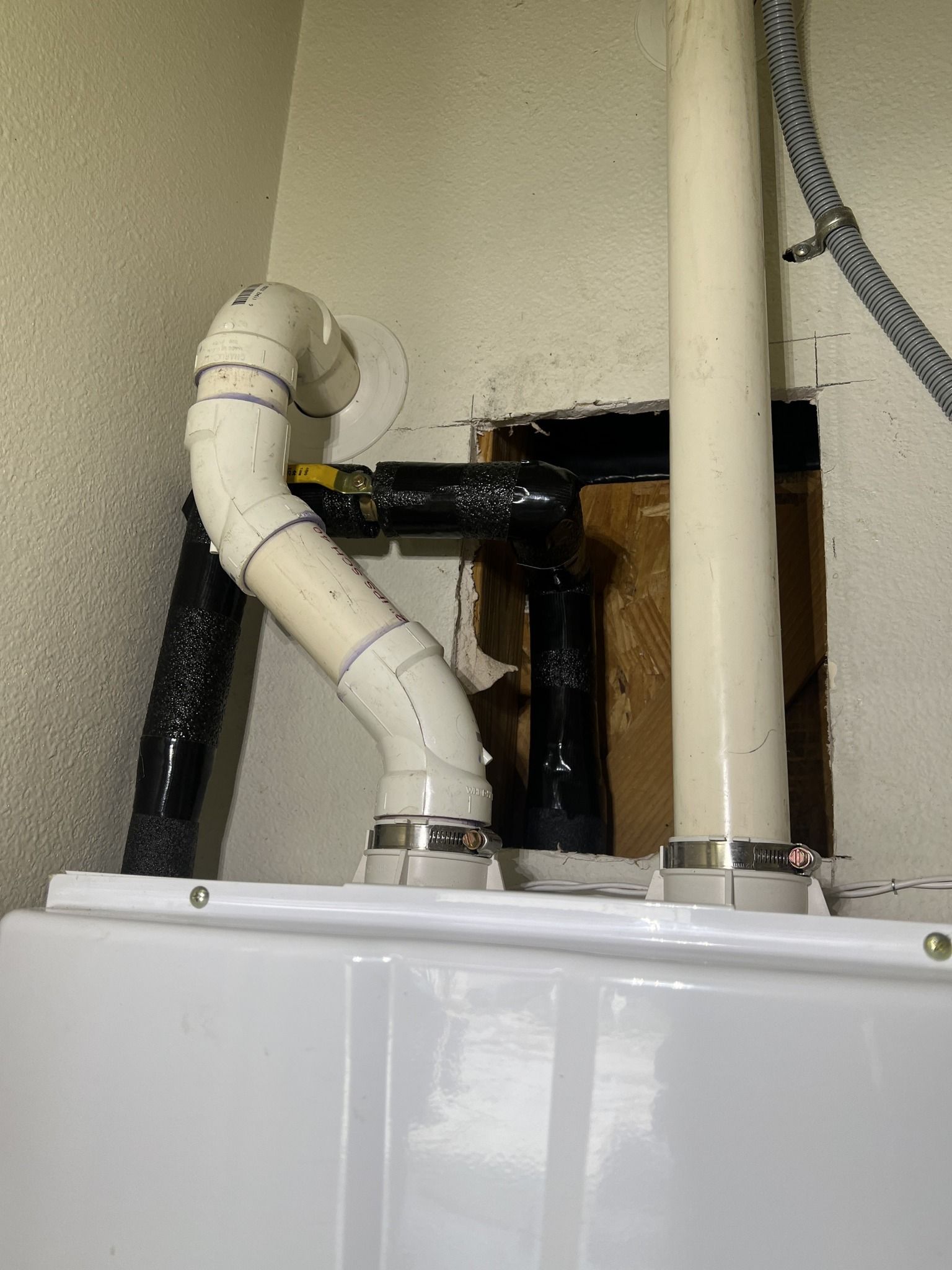 A close up of a washer and dryer with pipes coming out of it.