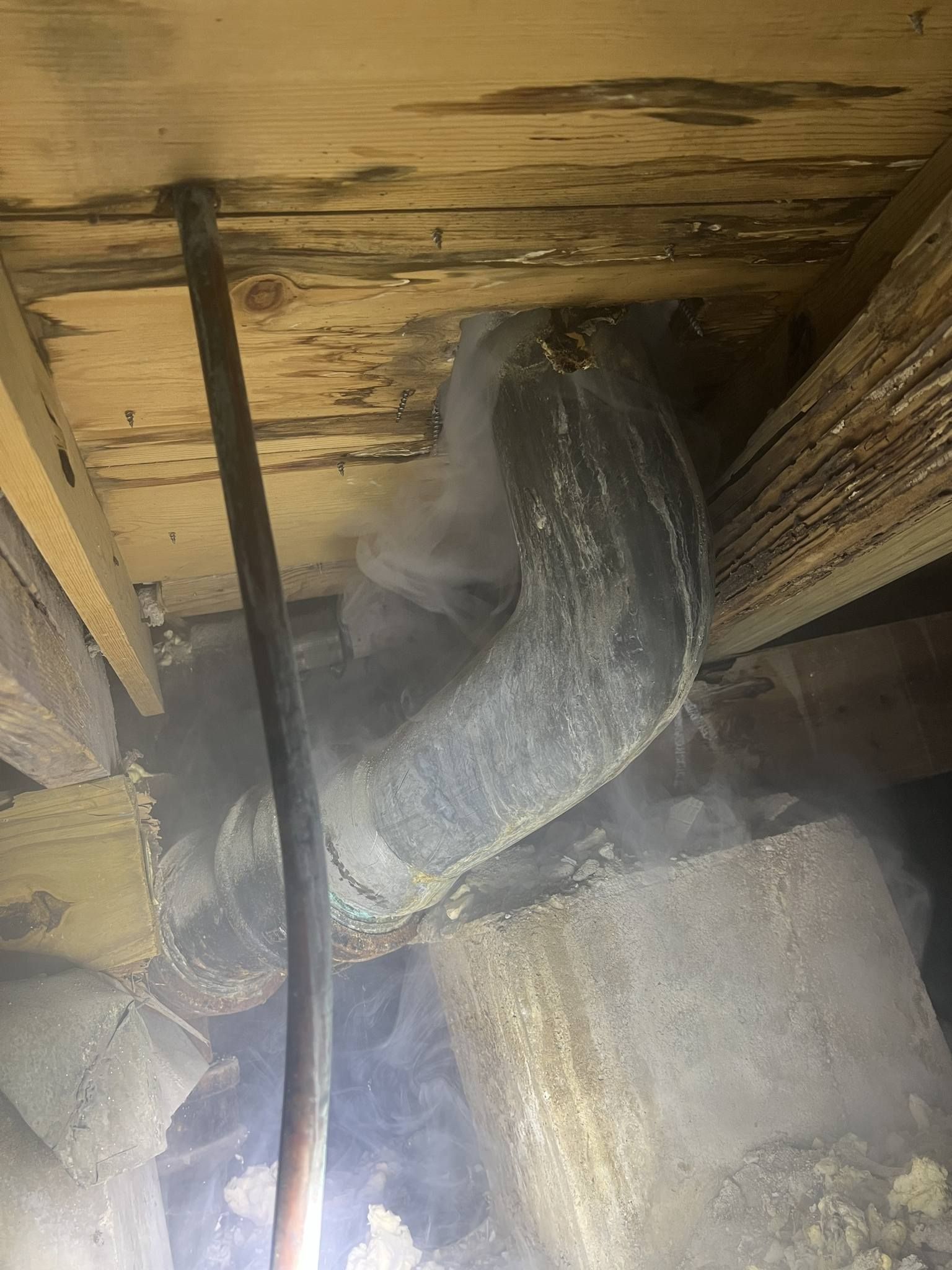 A pipe is hanging from the ceiling of a wooden building.