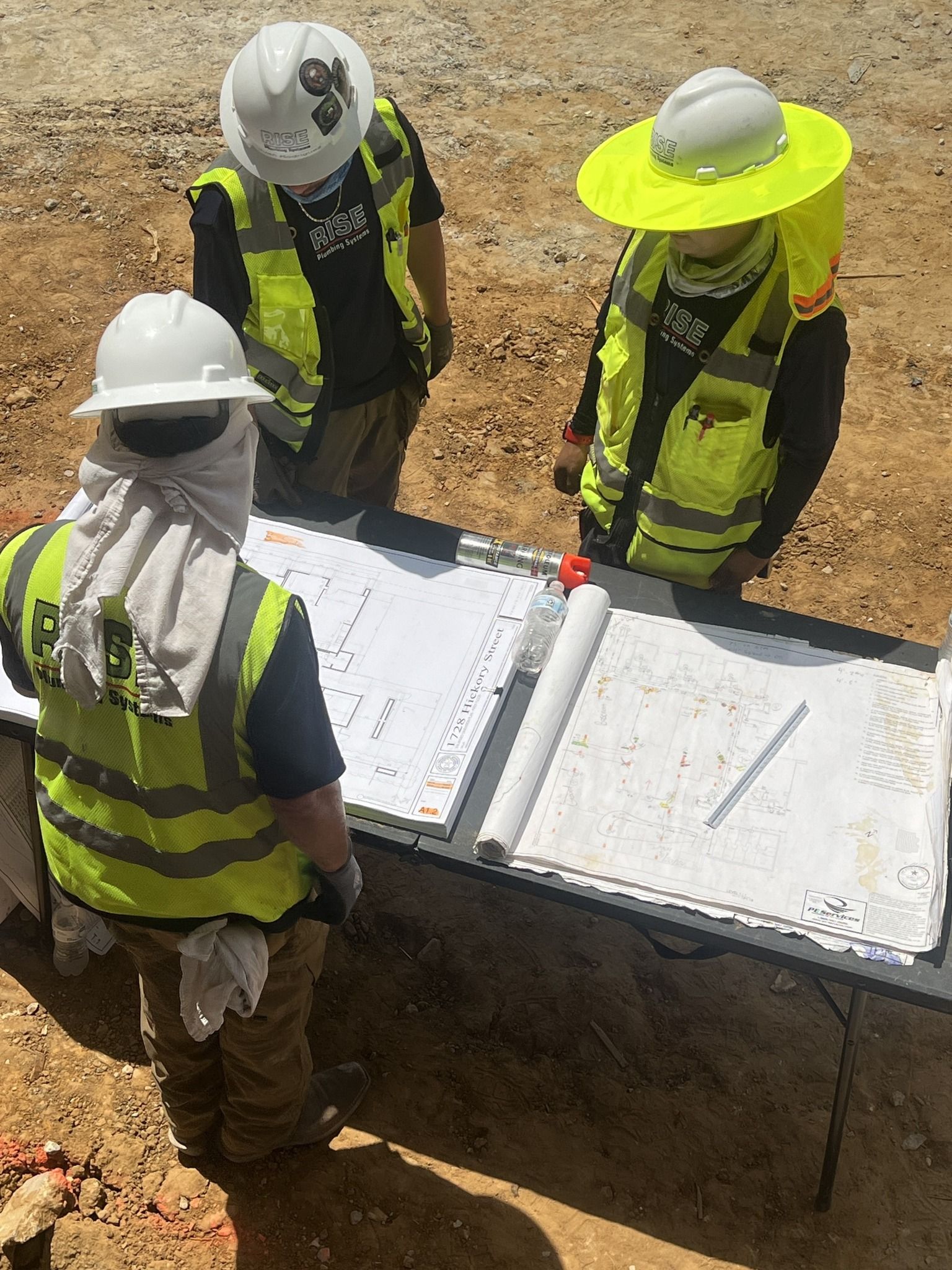 A group of construction workers are standing around a table looking at a blueprint.