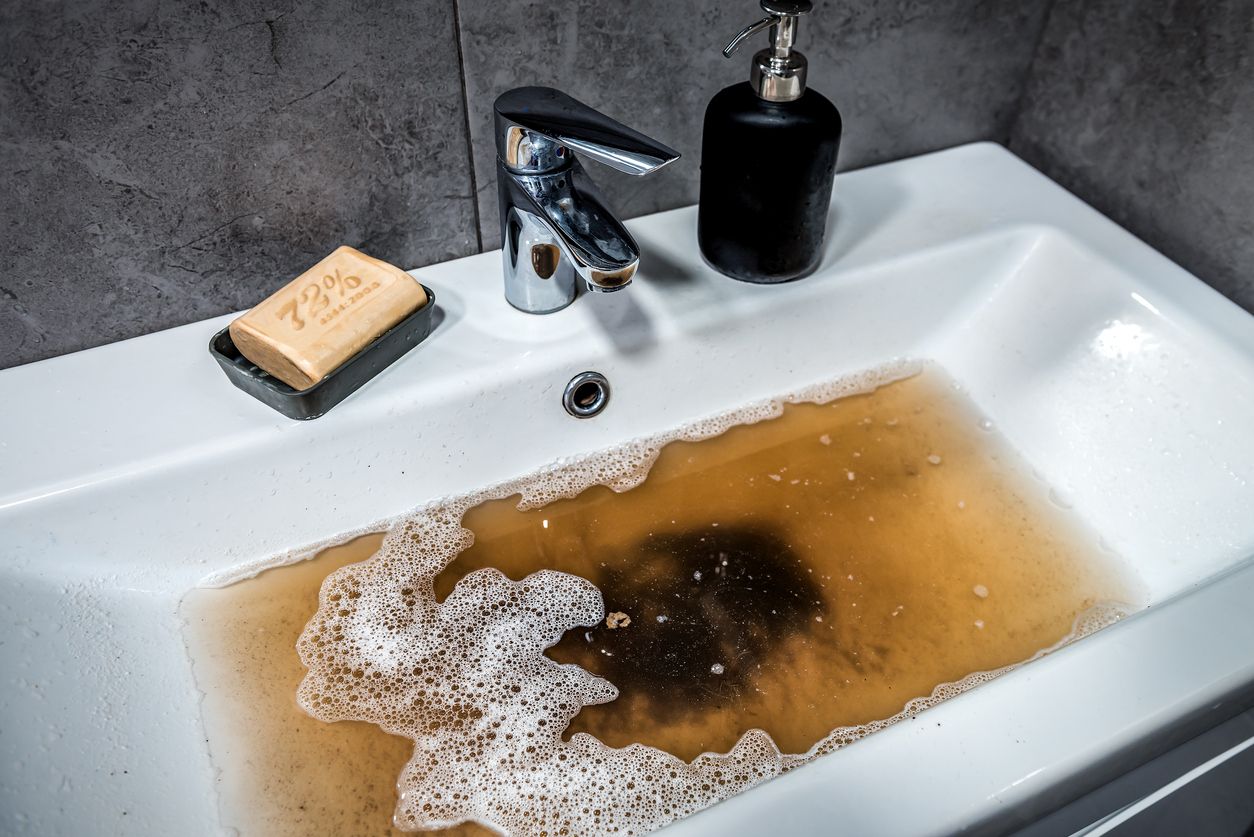A bathroom sink with brown water coming out of it.