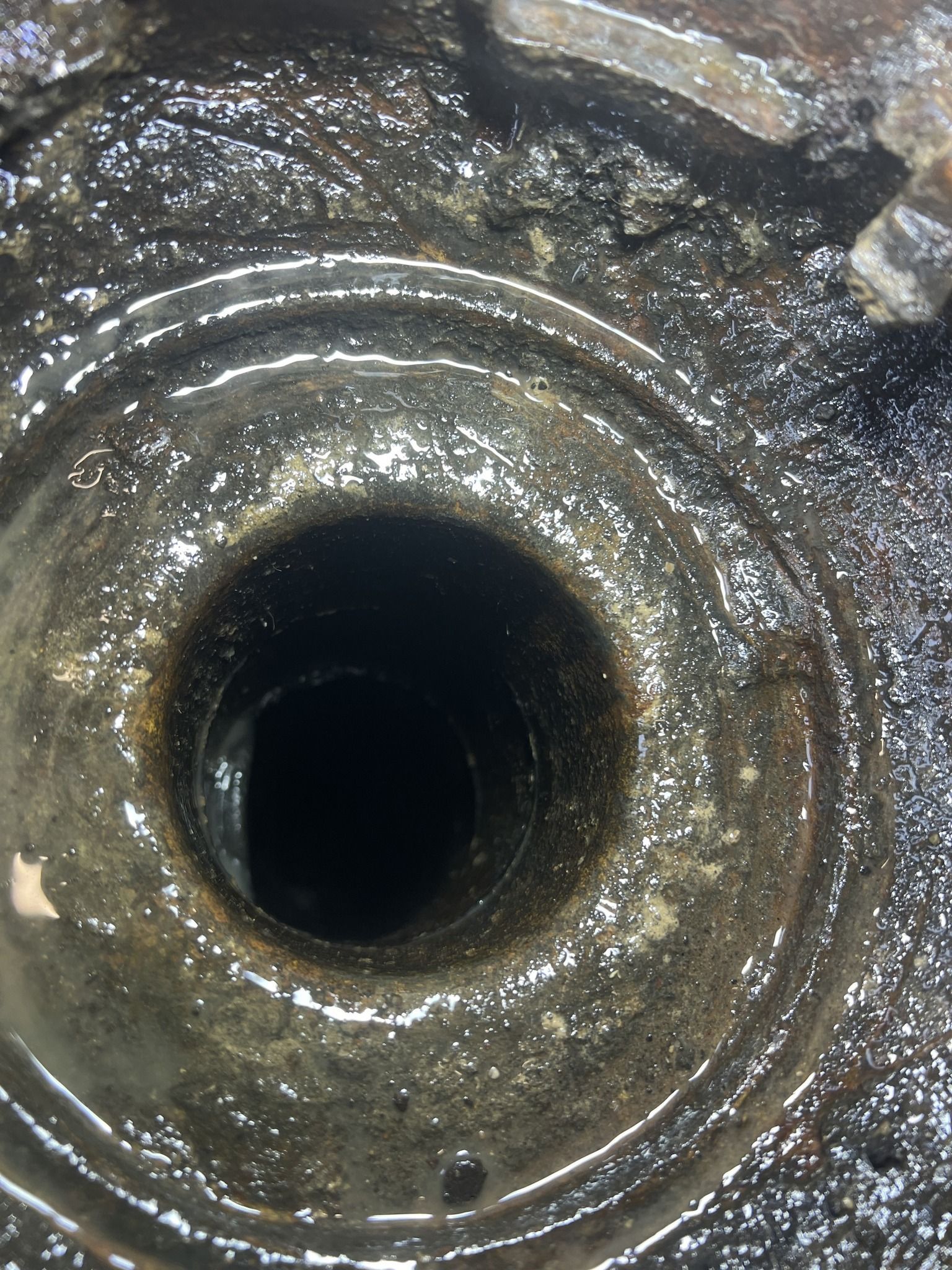 A close up of a drain with a hole in it.