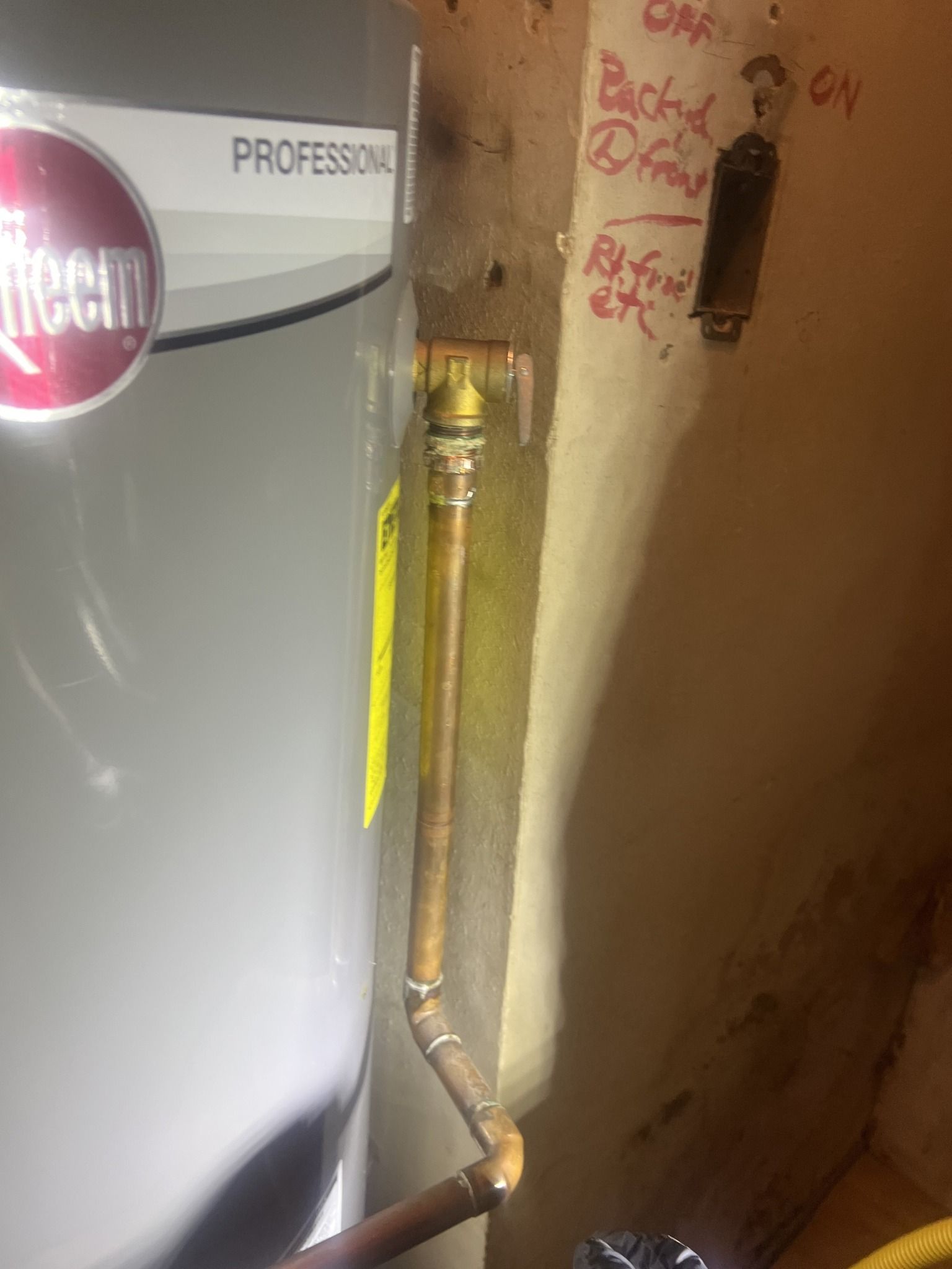 A water heater is sitting next to a copper pipe in a room.