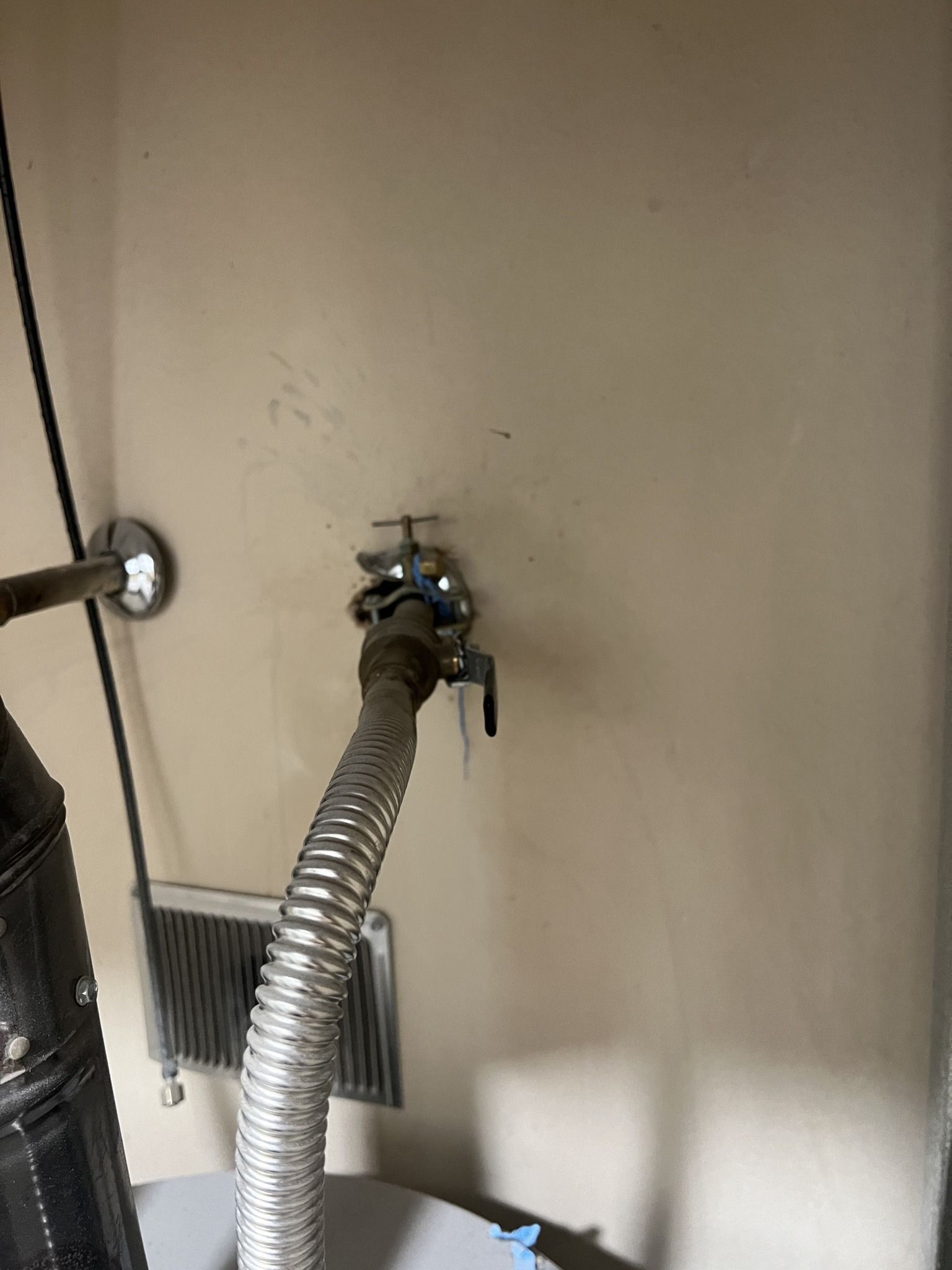 A hose is attached to a faucet on a wall.