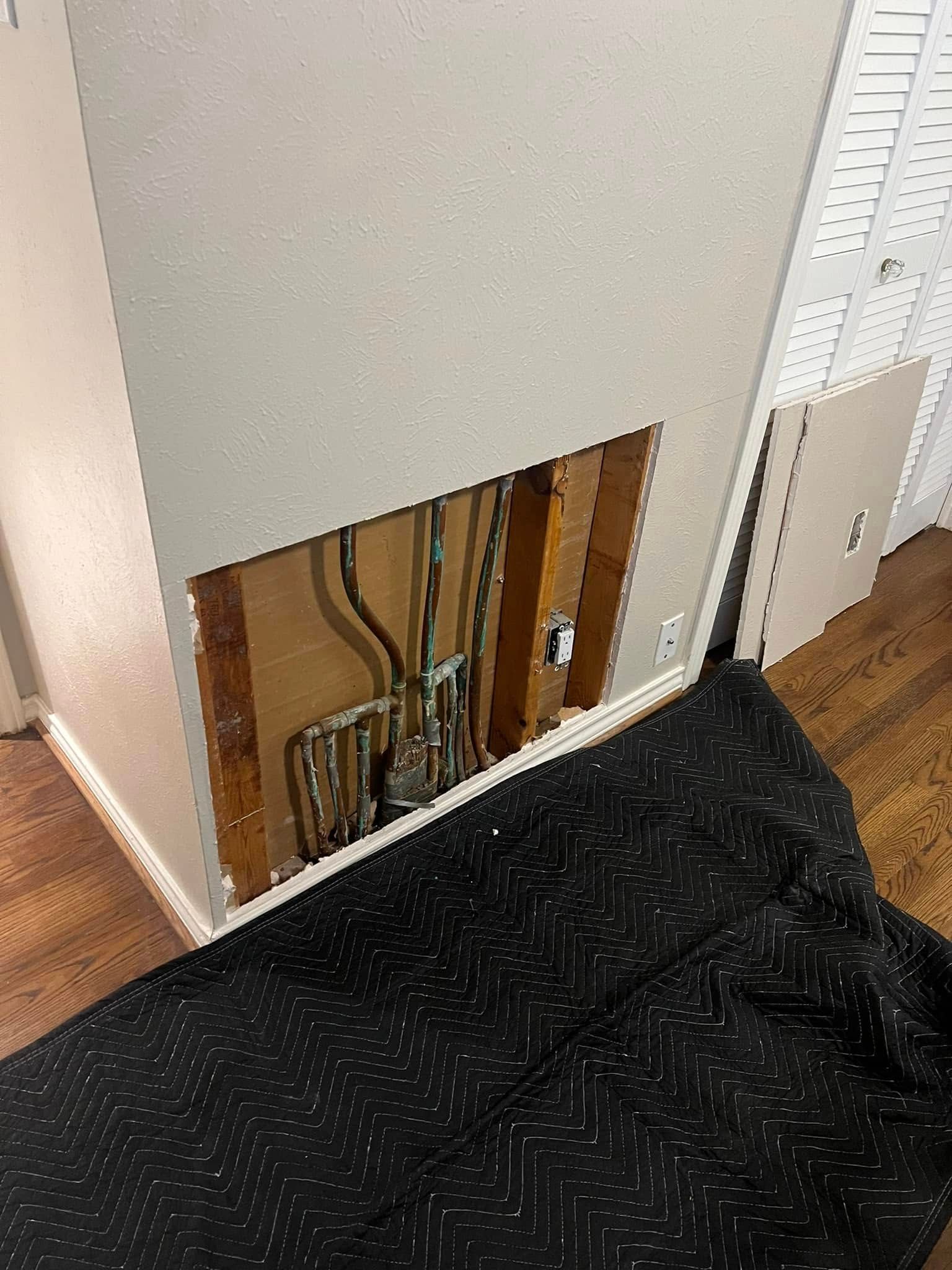 There is a hole in the wall with pipes coming out of it.