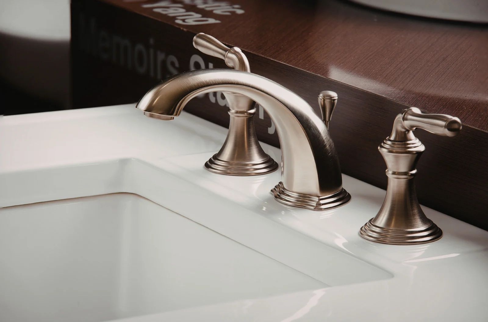 Brushed nickel bathroom faucet with two handles on a white sink.