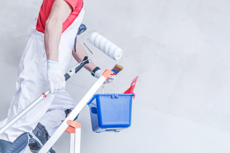 A Honolulu house painter coating a wall with a roller and a bucket.