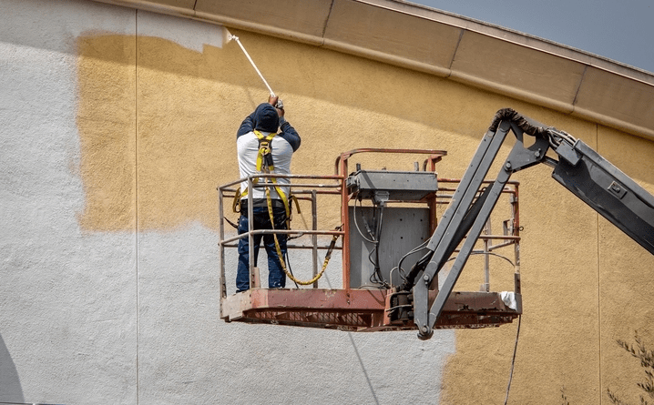 Honolulu commercial painter using spray gun on side of building