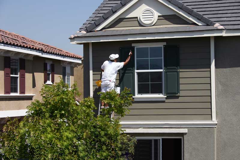 house painter in Oahu finishing exterior of tan brown home