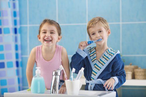 children brushing teeth while looking at mirror, preventing child tooth decay blog
