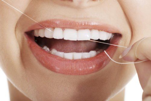 close up of a woman flossing teeth, importance of flossing blog
