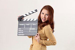 woman holding a clapperboard, dental trivia fun blog