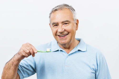 older man holding tooth brush, geriatric dental care blog