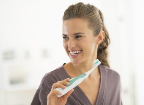 woman holding electric tooth brush, manual v. electric toothbrush blog