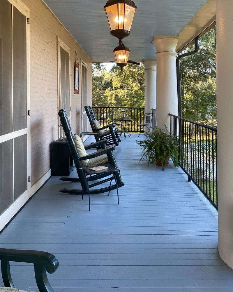 Porch with rocking chairs, painted floor and ceiling, lantern lights, and wrought iron railing.