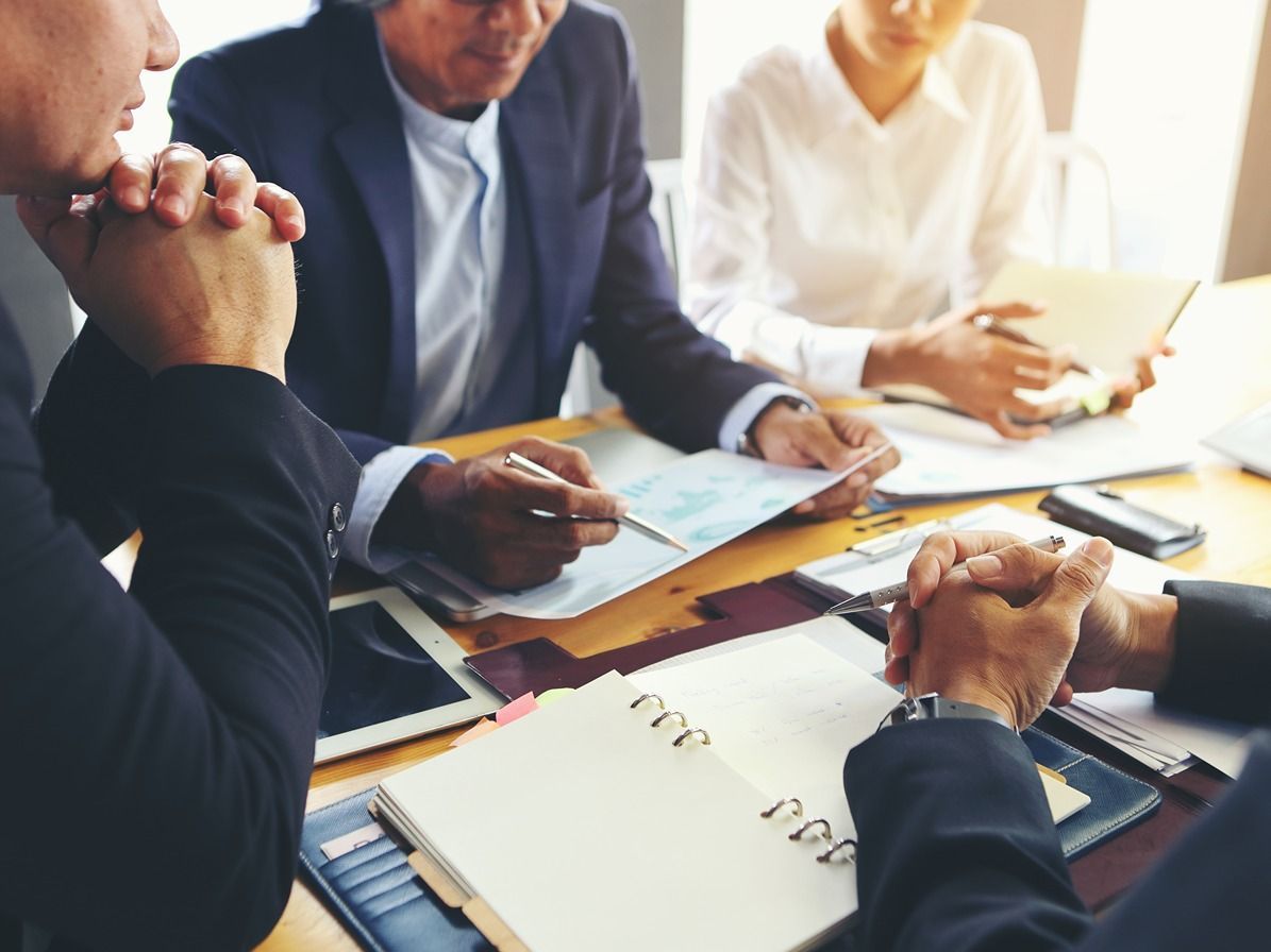 A group of business people are sitting around a table having a meeting.