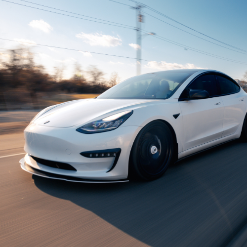 a white tesla model 3 is driving down a road
