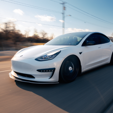 a white tesla model 3 is driving down a road